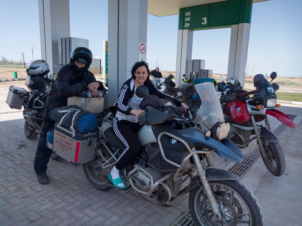 Emil megtartja a motort a benzinkút papucsos tündére alatt.
