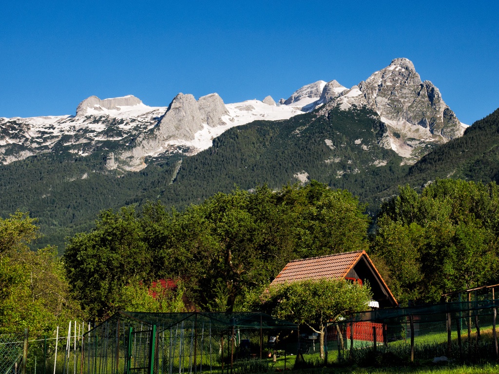 Bovec-i parasztház a háttérben a Triglav havas csúcsaival.